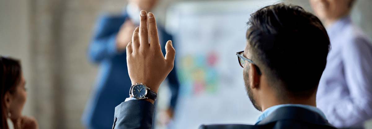 person in meeting raising hand in air